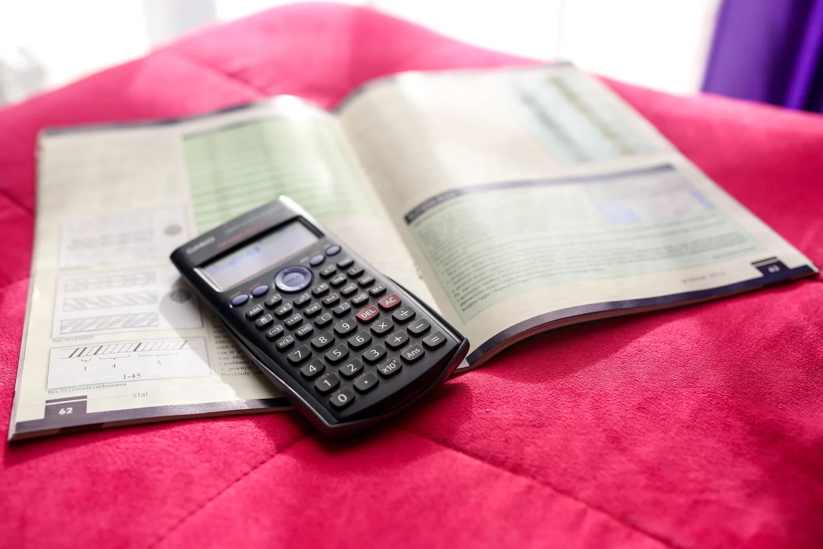 Calculator and a book on top of red fabric