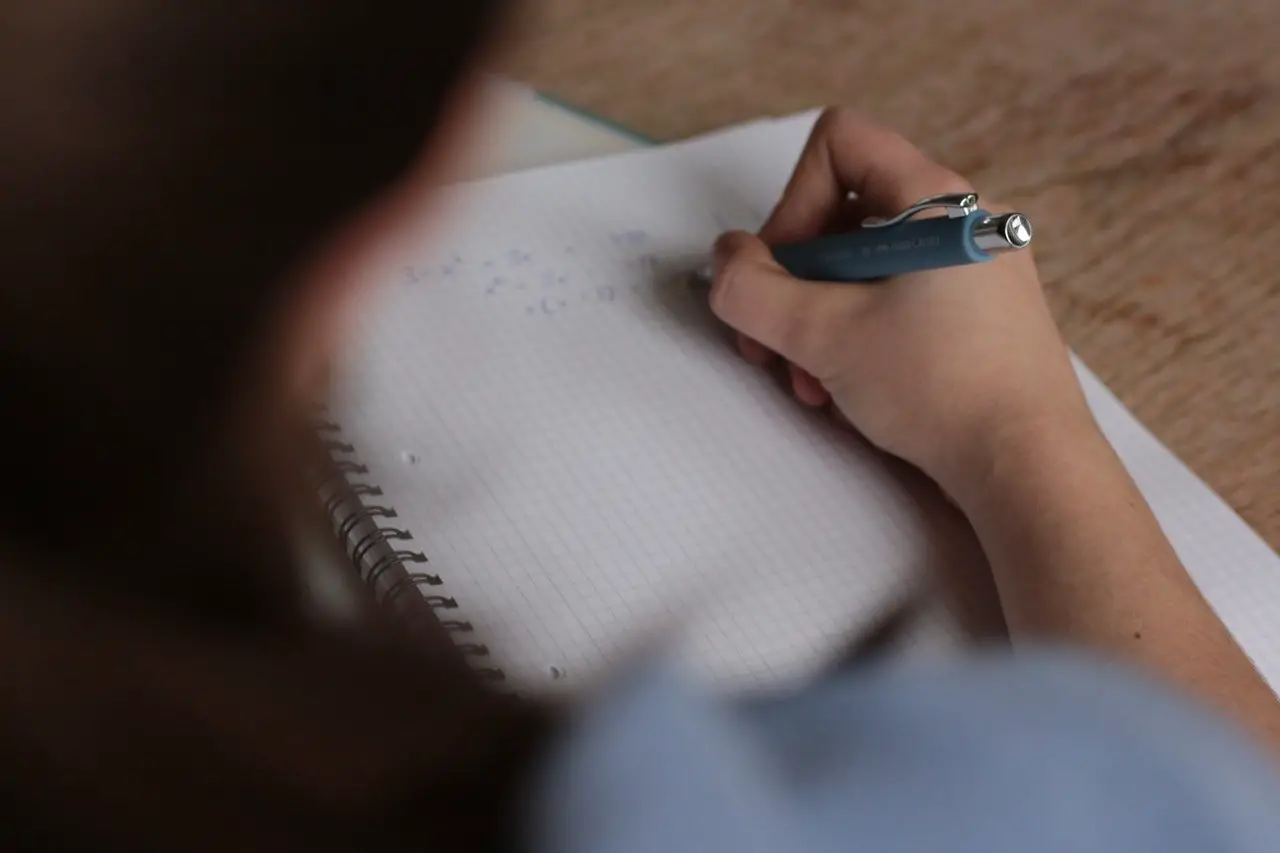Person writing on a white notebook